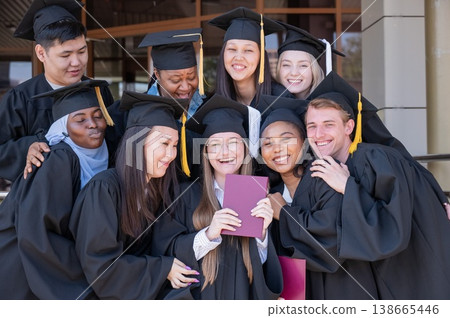 Happy students of different nationalities in graduation gowns hold their diplomas. Happy students of different nationalities in graduation gowns hold their diplomas. 138665446