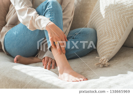 一位時尚的亞洲家庭主婦在客廳沙發上放鬆地躺著,露出她的雙腳。 一位時尚的亞洲家庭主婦在客廳沙發上放鬆地躺著,露出她的雙腳。 138665969