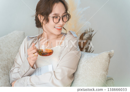 A stylish Asian woman sitting on the sofa in the living room and relaxing during tea time A stylish Asian woman sitting on the sofa in the living room and relaxing during tea time 138666033