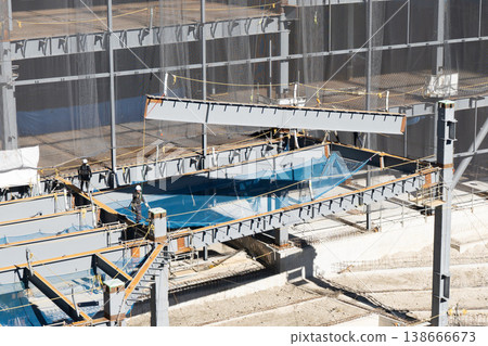 A scene from a steel frame construction site: lifting steel beams with a crane during the erection process (1) 138666673