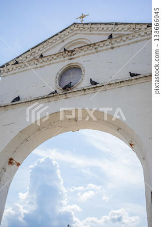 Architectural archway temple gate with pigeons perched under cloudy sky 138666945