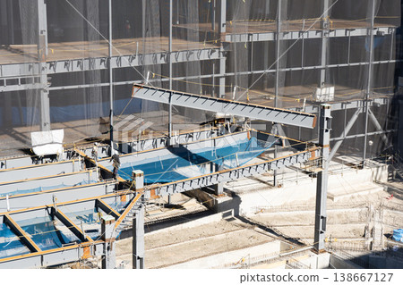 A worker guiding a suspended load with a rope and a crane lifting operation at a steel frame construction site (Image 1) A worker guiding a suspended load with a rope and a crane lifting operation at a steel frame construction site (Image 1) 138667127