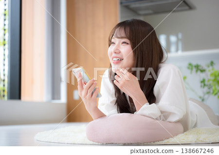 A woman relaxing at home, lying face down and looking at her smartphone. A woman relaxing at home, lying face down and looking at her smartphone. 138667246