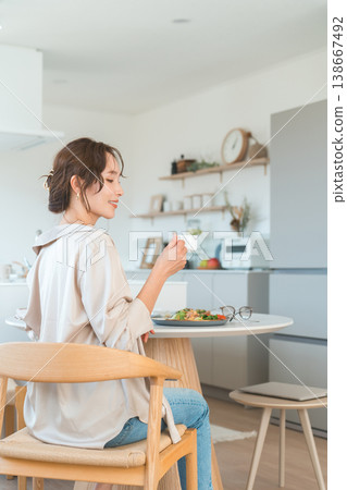 A smiling woman's profile as she eats at a dining table. A smiling woman's profile as she eats at a dining table. 138667492