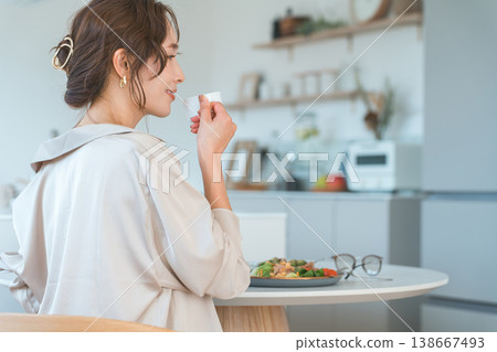 A smiling woman's profile as she eats at a dining table. A smiling woman's profile as she eats at a dining table. 138667493