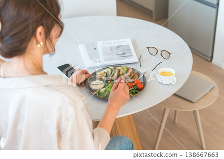 Rear view of a woman eating at the dining table Rear view of a woman eating at the dining table 138667663