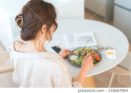 一位女士在餐桌旁用餐的背影 138667664