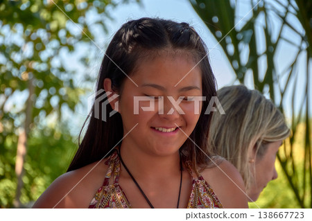 Close-up of a young Chinese woman smiling while enjoying a sunny day outdoors 138667723