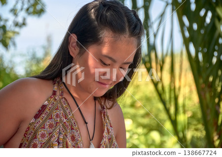 Close-up of a young Chinese woman smiling while enjoying a sunny day outdoors 138667724