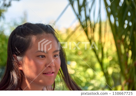 Close-up of a young Chinese woman smiling while enjoying a sunny day outdoors 138667725