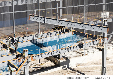 A worker guiding a suspended load with a rope and a crane lifting operation at a steel frame construction site (Image 7) A worker guiding a suspended load with a rope and a crane lifting operation at a steel frame construction site (Image 7) 138667774