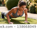 Determined young woman performing push-ups during outdoor fitness workout 138668049