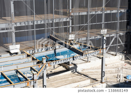 A worker guiding a suspended load with a rope and a crane lifting operation at a steel frame construction site (10) A worker guiding a suspended load with a rope and a crane lifting operation at a steel frame construction site (10) 138668149