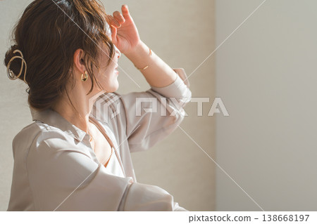 A profile view of a woman wearing gold accessories in a living room bathed in the setting sun (model, fashion, light, shadow) A profile view of a woman wearing gold accessories in a living room bathed in the setting sun (model, fashion, light, shadow) 138668197
