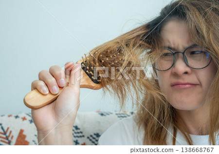 Asian woman having problem of her thick hair stuck while using her hair. Thick hair weights more than thin hair and prone to damage and frizzy. Asian woman having problem of her thick hair stuck while using her hair. Thick hair weights more than thin hair and prone to damage and frizzy. 138668767