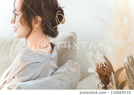 A profile view of a stylish Asian woman relaxing on a living room sofa. A profile view of a stylish Asian woman relaxing on a living room sofa. 138669510