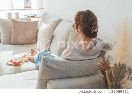 A stylish Asian woman sitting on a sofa and drinking tea 138669511