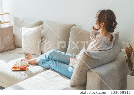 A stylish Asian woman sitting on a sofa and drinking tea 138669512