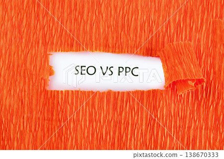 Words SEO VS PPC appear through a torn opening in a vibrant orange textured paper background. This highlights a comparison of digital advertising methods Words SEO VS PPC appear through a torn opening in a vibrant orange textured paper background. This highlights a comparison of digital advertising methods 138670333