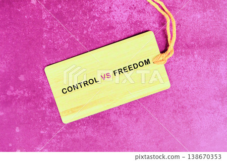 A rectangular yellow tag features the words Control VS Freedom in black and pink letters. It rests on a textured magenta background A rectangular yellow tag features the words Control VS Freedom in black and pink letters. It rests on a textured magenta background 138670353