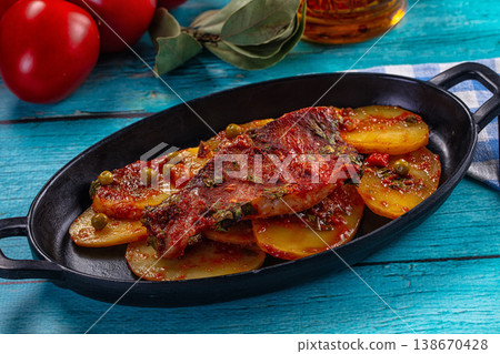 Baked fish fillet with tomato sauce and vegetables on a rustic blue wooden table 138670428