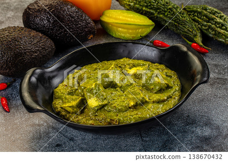 Palak Paneer, an Indian spinach and cottage cheese curry, served in a bowl with fresh vegetable ingredients. Palak Paneer, an Indian spinach and cottage cheese curry, served in a bowl with fresh vegetable ingredients. 138670432