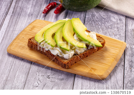 Avocado toast with cream cheese on a rustic wooden cutting board Avocado toast with cream cheese on a rustic wooden cutting board 138670519