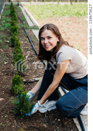 Woman plants thuja in the garden. Landscaping of the territory. Planting plants. gardening. 138670627
