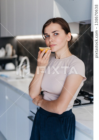 Young woman smelling a lemon slice in a modern kitchen. Healthy lifestyle Young woman smelling a lemon slice in a modern kitchen. Healthy lifestyle 138670638