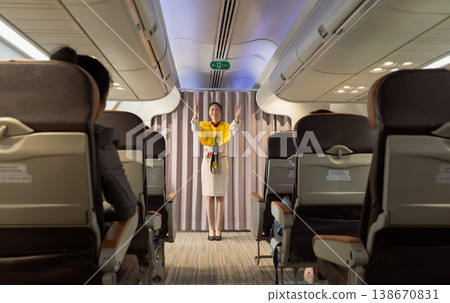 Flight attendant explaining safety regulations and showing the emergency exits to passengers on airplane cabin Flight attendant explaining safety regulations and showing the emergency exits to passengers on airplane cabin 138670831