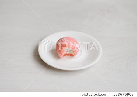 Bitten Pink Mochi Cake Showing White Cream Filling on Small White Saucer Bitten Pink Mochi Cake Showing White Cream Filling on Small White Saucer 138670905