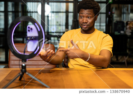 African American man pointing at smartphone while recording video blog African American man pointing at smartphone while recording video blog 138670940