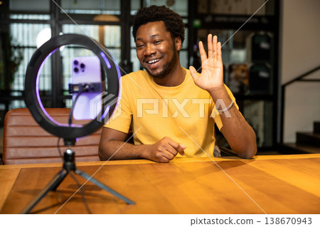 African American man waving hand to smartphone during live stream African American man waving hand to smartphone during live stream 138670943