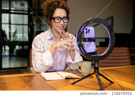 Smiling female host talking during live broadcast recording 138670958