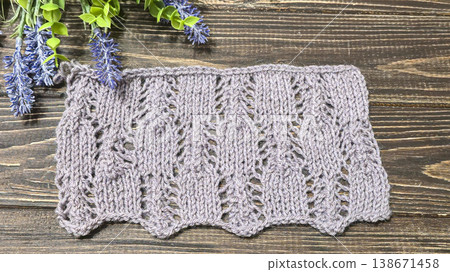 A raised openwork pattern knitted with colored yarn on a wooden background. A raised openwork pattern knitted with colored yarn on a wooden background. 138671458