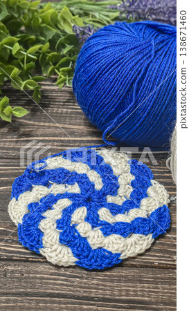 A raised openwork pattern knitted with colored yarn on a wooden background. A raised openwork pattern knitted with colored yarn on a wooden background. 138671460