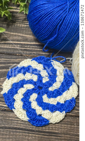 A raised openwork pattern knitted with colored yarn on a wooden background. A raised openwork pattern knitted with colored yarn on a wooden background. 138671472