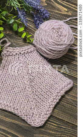 A raised openwork pattern knitted with colored yarn on a wooden background. A raised openwork pattern knitted with colored yarn on a wooden background. 138671480