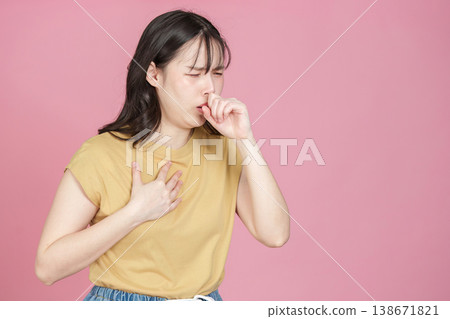 Young woman coughing and holding chest against pink background Young woman coughing and holding chest against pink background 138671821