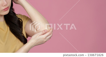 Young woman examining arm against pink background 138671826