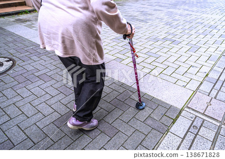 A shuffling gait in the urban landscape of Yokohama, Japan... through gaps... An elderly woman with a cane walks along a long paved sidewalk... What is life? = Yokohama city 138671828