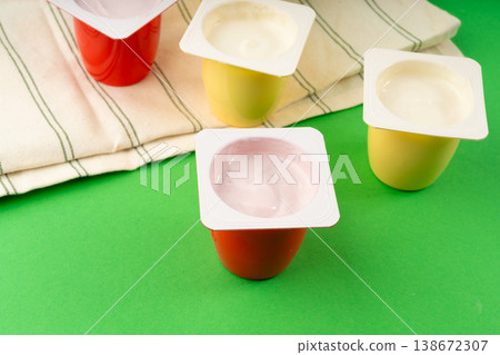 Yogurt cups set, pink and yellow fruit yoghurt in plastic pots, milk pudding container with spoon 138672307