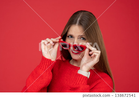 Smiling young woman with freckles holding red sunglasses near her face Smiling young woman with freckles holding red sunglasses near her face 138672541