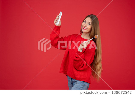 Cheerful young woman with freckles applying makeup with brush while looking in small mirror Cheerful young woman with freckles applying makeup with brush while looking in small mirror 138672542
