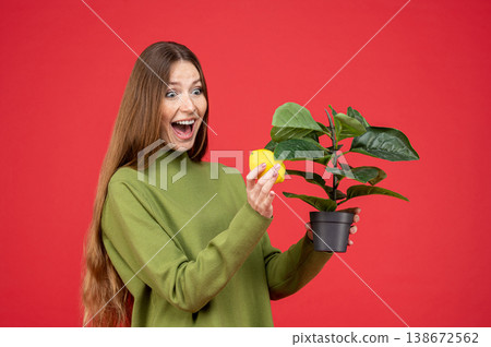 Surprised excited woman holding lemon and houseplant with open mouth 138672562