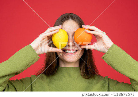 Cheerful woman hiding eyes with citrus fruits 138672575