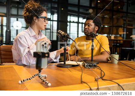Woman gesturing while filming podcast with colleague Woman gesturing while filming podcast with colleague 138672618