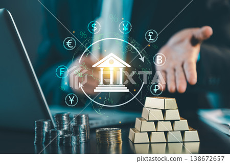 Businessman hand showing bank icon with global currency symbols and gold bars on table, central bank and international finance investment concept. Businessman hand showing bank icon with global currency symbols and gold bars on table, central bank and international finance investment concept. 138672657