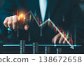 Businessman pointing at falling stock market chart with downward red arrows and stacks of coins, financial crisis and economic recession concept. 138672658