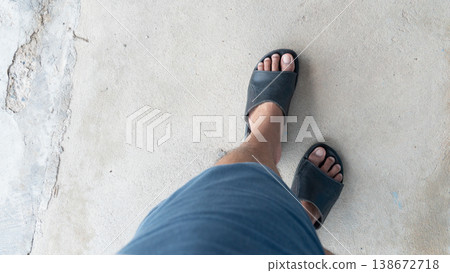 Above view of man wearing shorts and black leather sandals is walking on the ground. Standing on old cement floor. 138672718